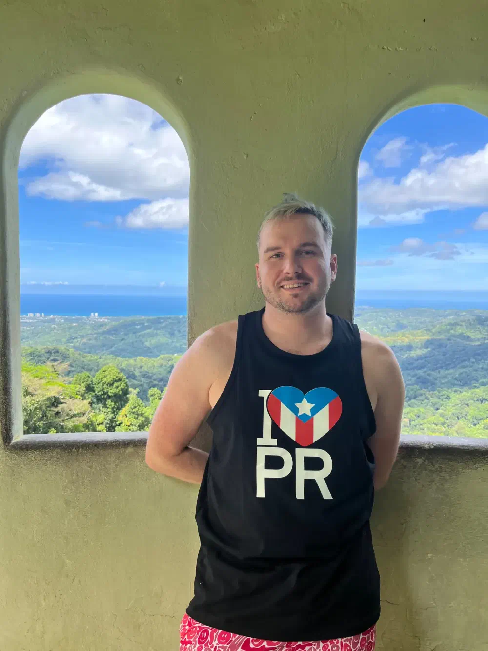 Standing in an arched viewing platform overlooking tropical hills meeting the sea