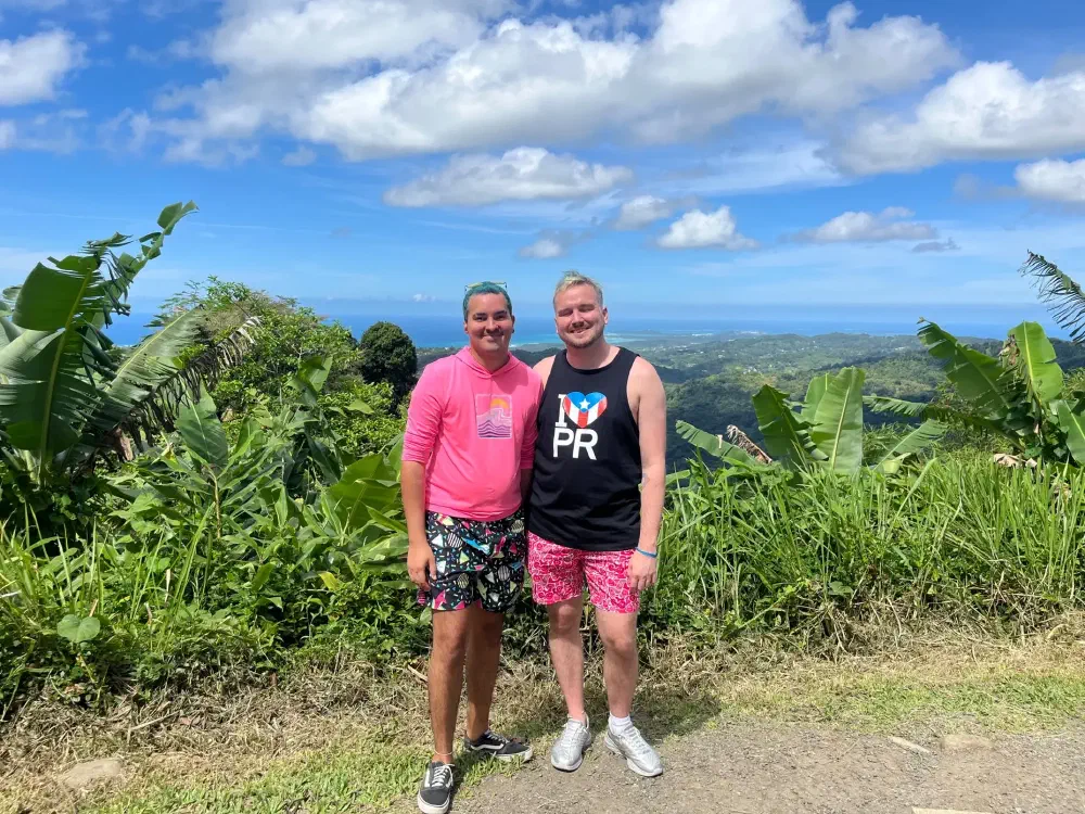 Two men on a trail overlooking ocean and green coastline